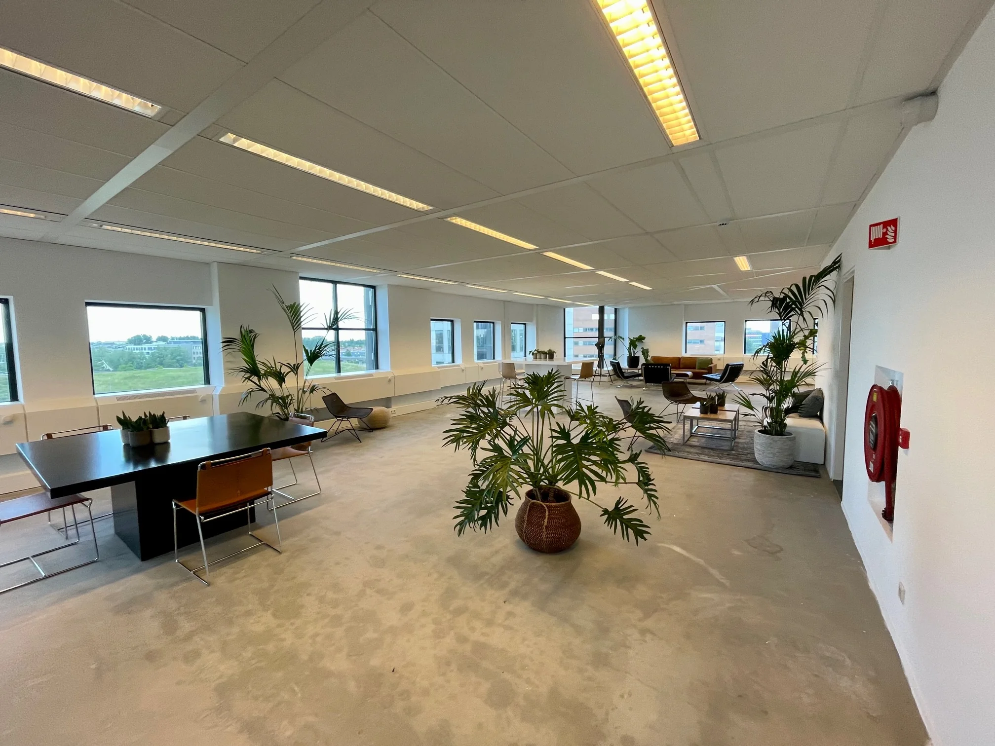 Moderne, open kantoorruimte in Rivium Quadrant met zitgedeeltes, vergadertafel en veel groen.